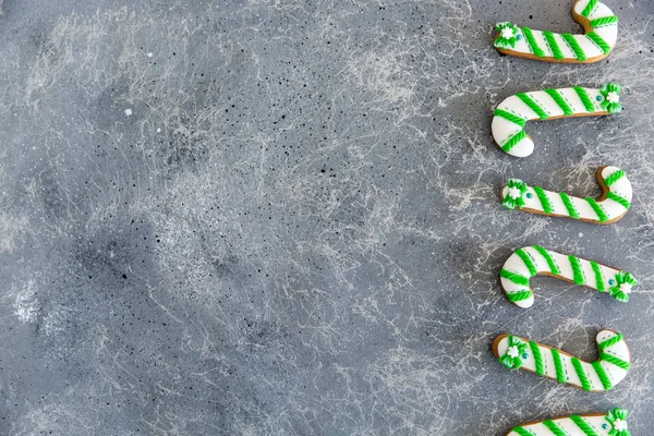 Hand bemalte Weihnachtslebkuchen grün und weiß Zuckerrohr auf einem schönen grauen Hintergrund. Kartenkonzept. Ansicht von oben. flache Lage. — Stockfoto