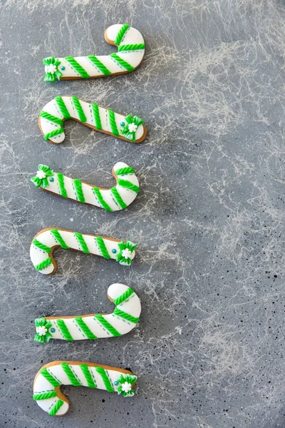 Hand bemalte Weihnachtslebkuchen grün und weiß Zuckerrohr auf einem schönen grauen Hintergrund. Kartenkonzept. Ansicht von oben. flache Lage. — Stockfoto