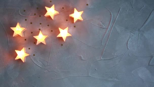 Yılbaşı dekoratif yıldızları mumları, gri dokuların arka planında parıldıyor. — Stok video