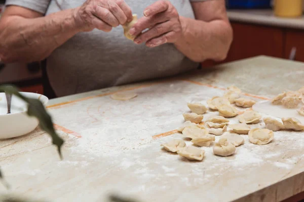 Руки старухи на кухне делают пельмени — стоковое фото
