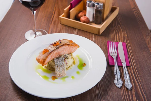 Gourmet roasted salmon steak baked in the oven, served on a pillow of risotto and red caviar as a delicious seafood dish for dinner
