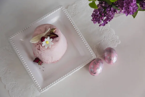 Pink Easter from the pressed cottage cheese with sweet dessert surprise for Easter holiday on white plate with pink eggs vase with lilac flowers on the table. Flat lay — Stock Fotó