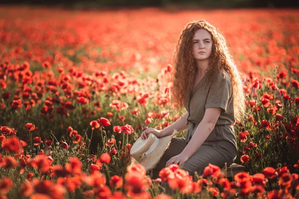 Jovem menina bonita vermelho-ouvir no campo de papoula vermelha — Fotografia de Stock