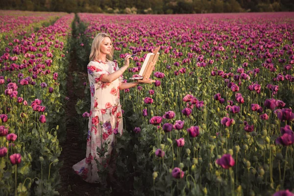 Piękna szczęśliwa kobieta z długimi włosami w białej sukience malowanie w polu Liliowy Poppy Flowers — Zdjęcie stockowe