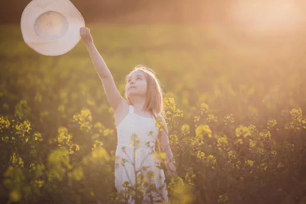 Menina adorável em vestido branco e chapéu no campo de primavera de flores amarelas, estupro — Fotografia de Stock