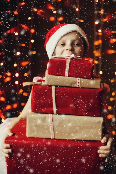 Söt flicka i tomtens hatt förbereder presenter till familjen till jul. — Stockfoto