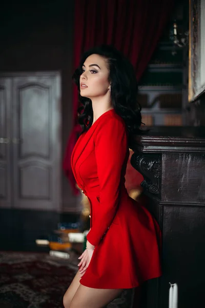 Sexy brunetka kobieta noszenie w czerwony uwodzicielski opierając się na ścianie. — Zdjęcie stockowe