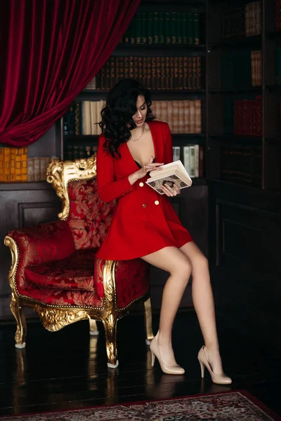 赤の上に座って、本を持ってエレガントなブルネット. — ストック写真