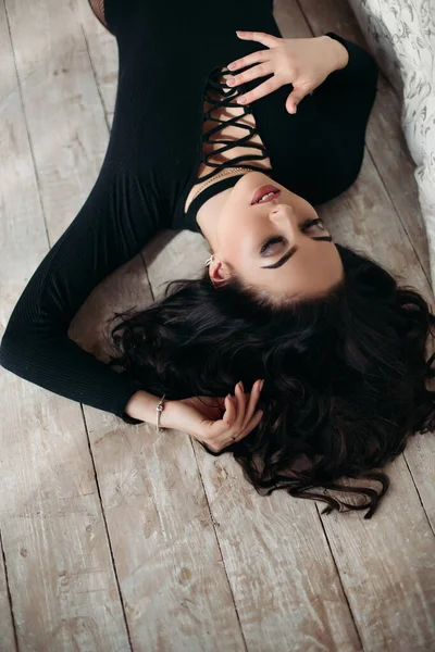 위에서 내려다보면 검은 바닥에 누워 있는 아름다운 갈색 머리 여인. — 스톡 사진