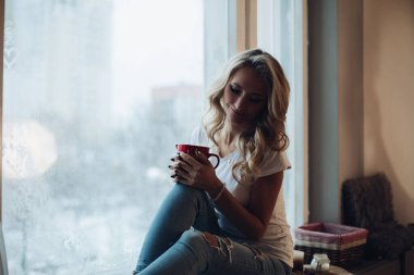 Pencere pervazında oturan güzel sarışın..