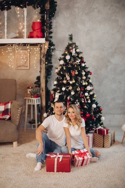 Loving couple with presents against the Christmas tree. — Stock Photo, Image