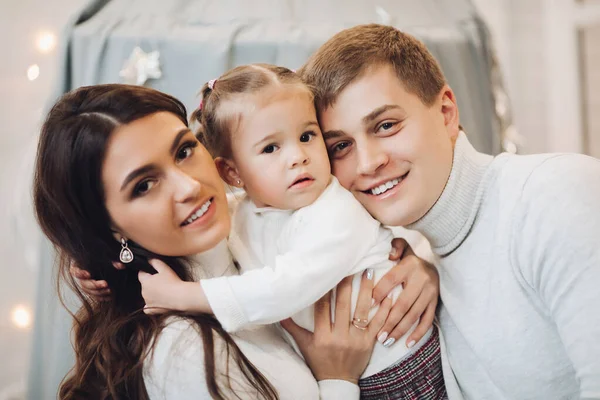 Hermosa familia caucásica en Christmas.Brunette madre y padre con adorable hija sonriendo a la cámara . —  Fotos de Stock