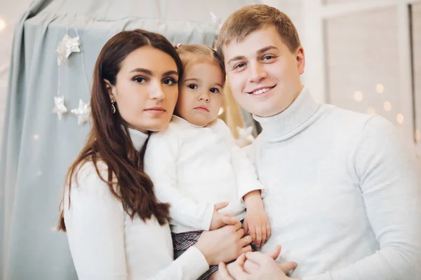 Hermosa familia caucásica en Christmas.Brunette madre y padre con adorable hija sonriendo a la cámara . —  Fotos de Stock