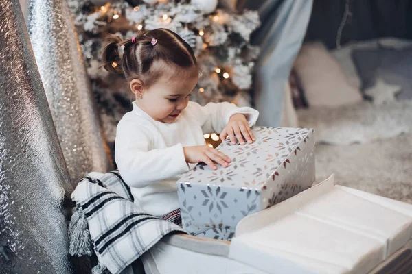 Preciosa niñita desenvolviendo el regalo en Navidad . — Foto de Stock