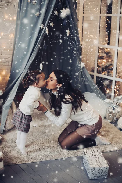 Madre e hija besándose en Navidad bajo la nieve . —  Fotos de Stock