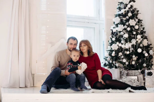 Familia feliz bajo la nevada junto al árbol . —  Fotos de Stock