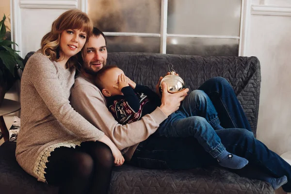 Leende familj med son på soffan. Kvinna och man ler mot kameran. — Stockfoto