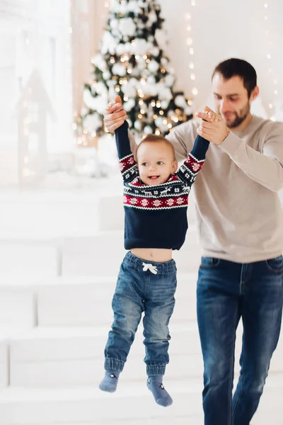 Padre besando a su adorable hijo contra un árbol de Navidad desenfocado . —  Fotos de Stock