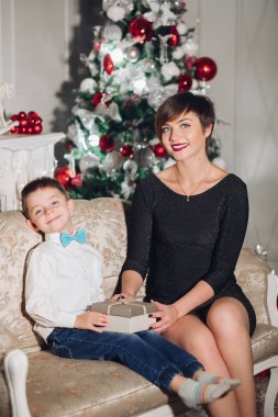 Güzel annesi olan bir çocuk Noel için dekore edilmiş stüdyoda sarılıyor..