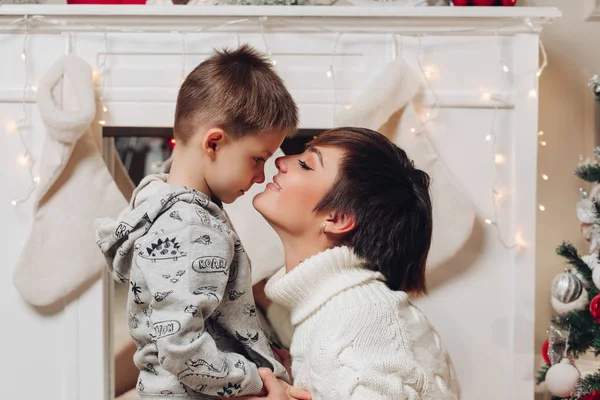 Niño con hermosa mamá abrazando en estudio decorado para Navidad. —  Fotos de Stock