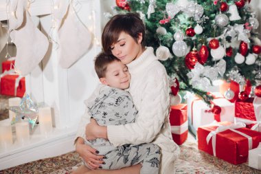 Güzel annesi olan bir çocuk Noel için dekore edilmiş stüdyoda sarılıyor..