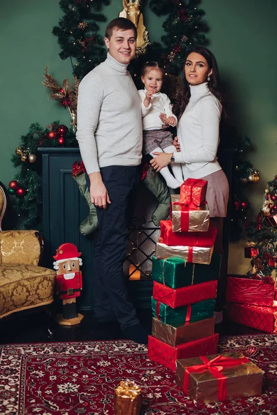 Retrato de familia caucásica feliz con regalos posando junto a la chimenea . —  Fotos de Stock