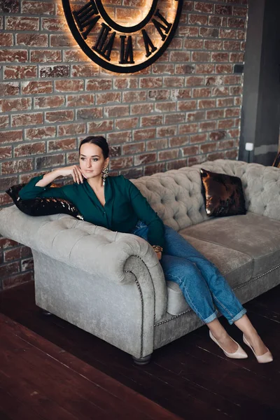 Елегантна молода жінка сидить на дивані в квартирі лофт . — стокове фото