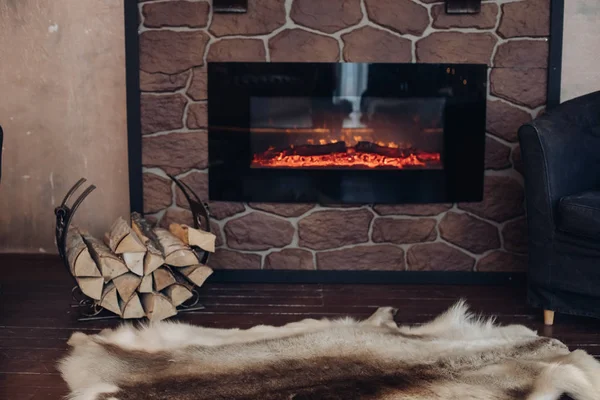 Acogedora habitación con chimenea, piel de piel y montón de bosques . — Foto de Stock