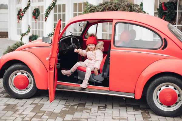 Sonriendo linda chica de invierno en sombrero rojo sentado en el coche divirtiéndose — Foto de Stock