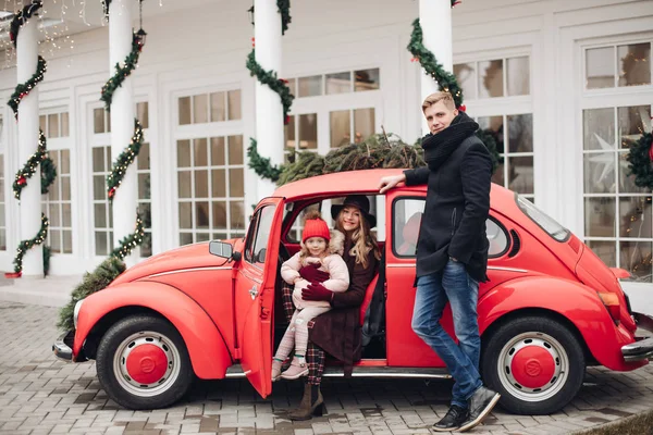 크리스마스 때 밖에 빨간 차를 타고 있는 멋진 가족들. — 스톡 사진