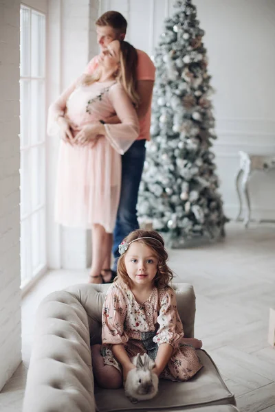 Emocionado chica con conejito contra abrazar a los padres . — Foto de Stock