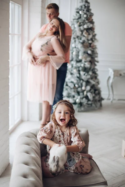 Emocionado chica con conejito contra abrazar a los padres . — Foto de Stock