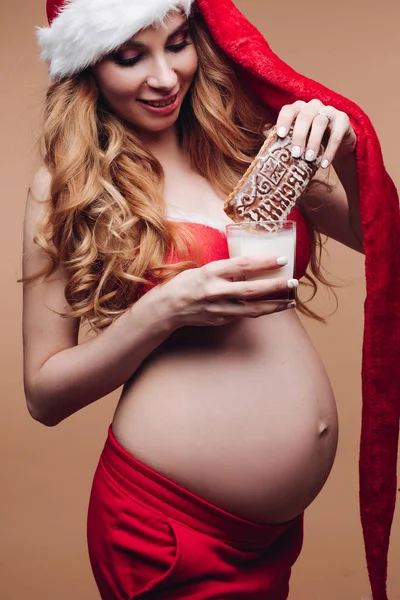 幸せな若いです妊娠中の女性はミルクとジンジャーブレッドのガラスを保持 — ストック写真