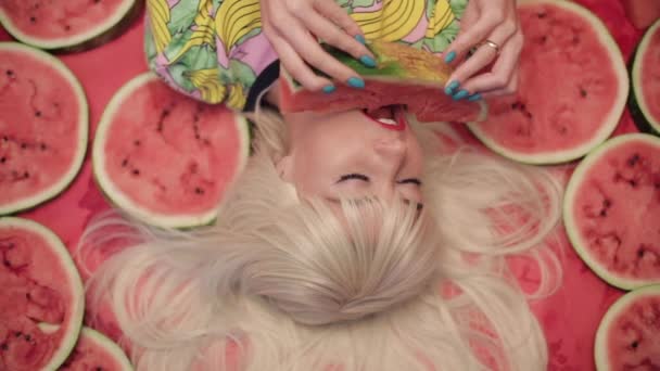 Ωραία ξανθιά ξαπλωμένη στο πάτωμα και τρώγοντας ζουμερό γλυκό καρπούζι — Αρχείο Βίντεο