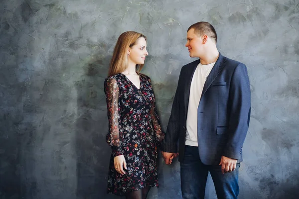 Casal elegante e feliz tocando uns aos outros por mãos, posando para a câmera . — Fotografia de Stock