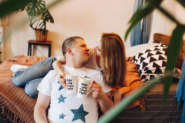 Pareja joven acostados juntos en el vientre en la cama en el estudio . —  Fotos de Stock