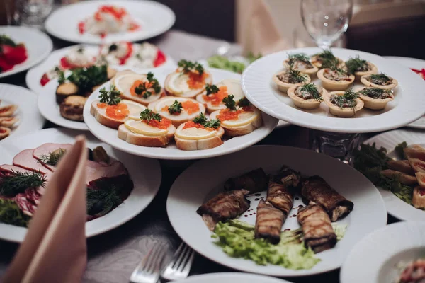 Läckra mellanmål på tallrikar vid banketten. Olika sorters kalla snacks serveras på tallrikar vid bankett. — Stockfoto