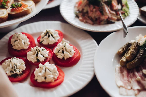 Lahodná rajčata se smetanovým sýrem. Různé studené občerstvení podávané na talířích na banketu. — Stock fotografie