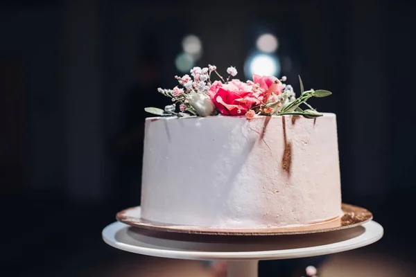 Bolo de casamento bonito decorado com flowers.flowers no topo em luz artificial . — Fotografia de Stock