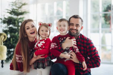 Mutlu beyaz takım elbiseli güzel kadın Noel ağacının yanında poz veriyor.