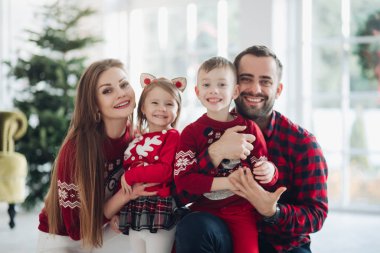 Mutlu beyaz takım elbiseli güzel kadın Noel ağacının yanında poz veriyor.