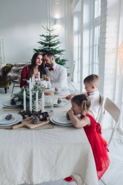 Mutlu genç aile evdeki şenlik masasında oturuyor.
