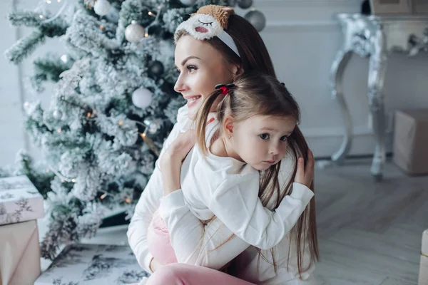 아름다운 크리스마스 트리 장식에 함께 앉아 즐거운 축제를 벌이고 있는 엄마와 딸 — 스톡 사진