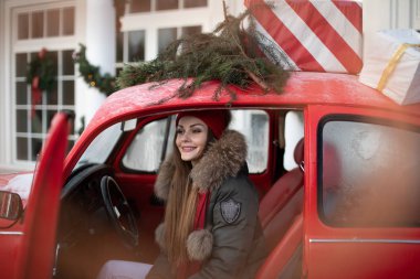Belarus Minsk 16: 12: 2019: Hoş, modaya uygun, kış kızı, kar taneleriyle çevrili kırmızı klasik arabaya poz veriyor.