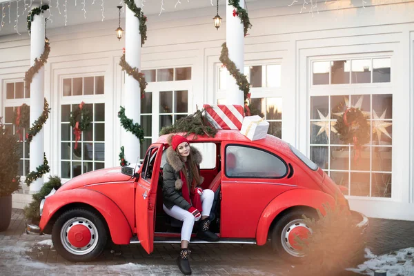 Belarus Minsk 16 12 2019:Pleasant fashionable winter girl smiling posing at red vintage car surrounded by snowflakes — 스톡 사진