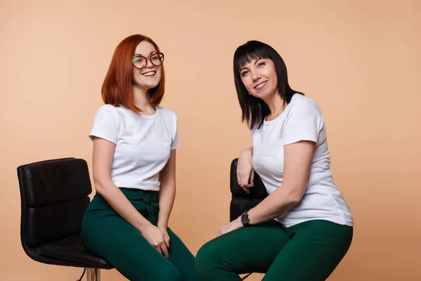 Dos alegre chica amigo riendo chismorreo sentado silla aislado en estudio fondo — Foto de Stock