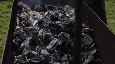 Kamp ateşinde, kül külleriyle çevrili kızgın kömürlerin yakın çekimi.