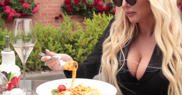 Primeros planos de la moda rubia sexy mujer usando gafas de sol comiendo pasta italiana apetitosa en la cafetería al aire libre — Vídeos de Stock