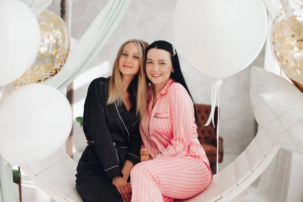 Dos amigas felices en pijama sentadas en un elegante sillón en un interior de lujo — Foto de Stock