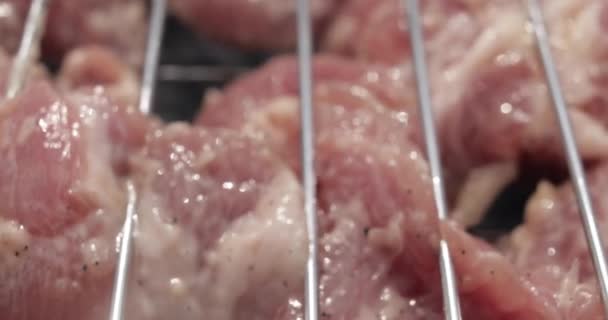 Carne roja cruda del bocadillo del primer plano extremo en la rejilla metálica de la parrilla zoom en imágenes de 4k — Vídeo de stock